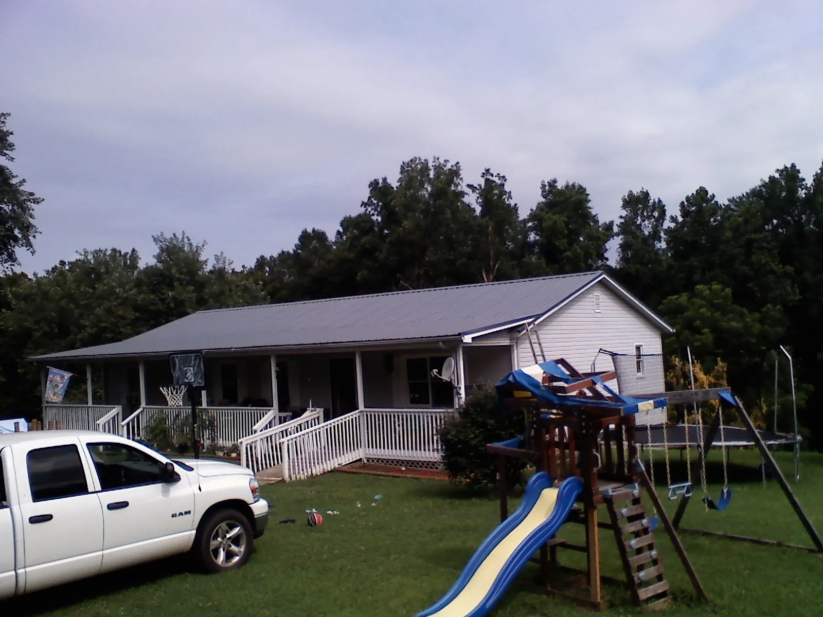 Dark metal roof on a country home with a full length front porch in Moneta