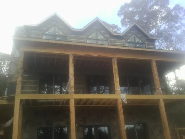 Dormers and porch framing on a large log home under construction — Roof Coating work by our crew in Moneta