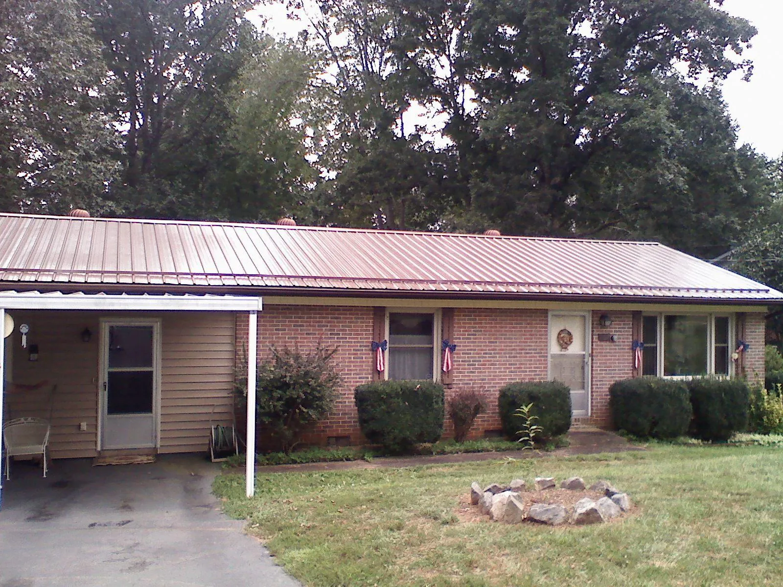 Bronze metal roof and carport on a brick ranch home — Roof Repair work by our crew in Moneta