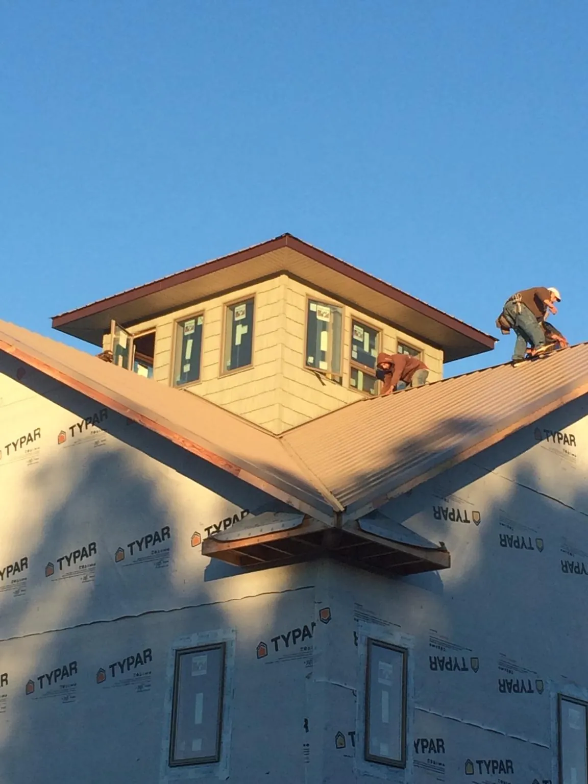 Roofers working around a rooftop cupola on a new metal roof at sunset — Roof Waterproofing in Moneta by Roofing Brothers